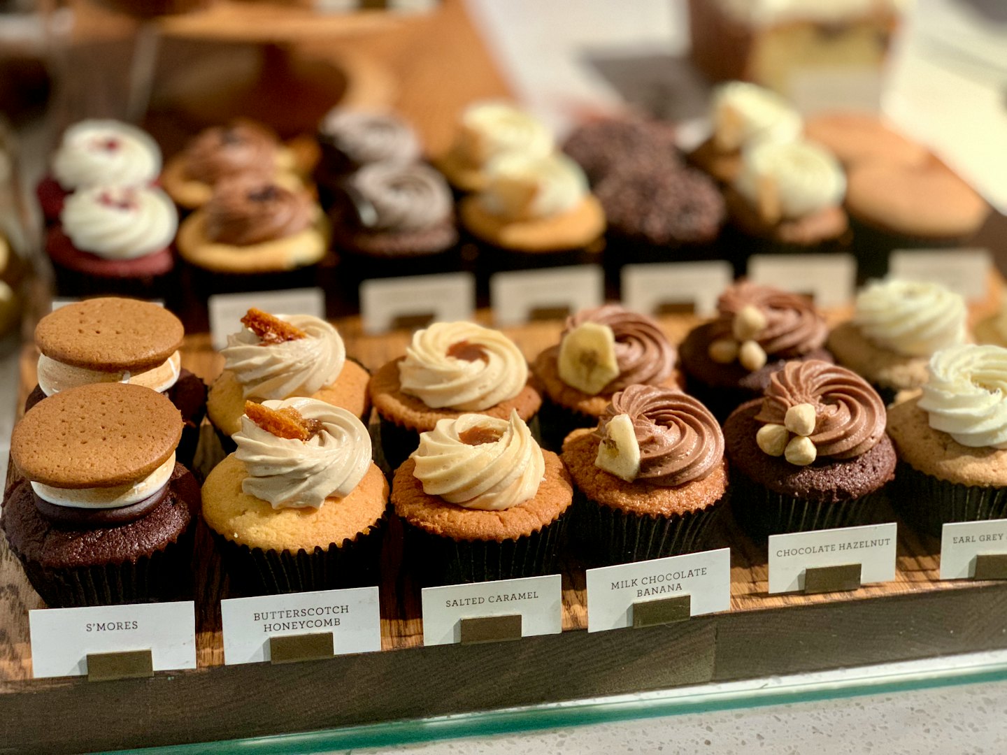 Gourmet cupcakes with unique toppings on a wooden stand.